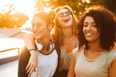 Üç neşeli genç ve güzel kız parkta eğleniyor