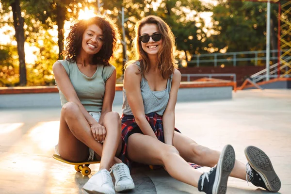 Two Smiling Young Girls Having Fun While Sitting Skateboard Park — Stock Photo, Image