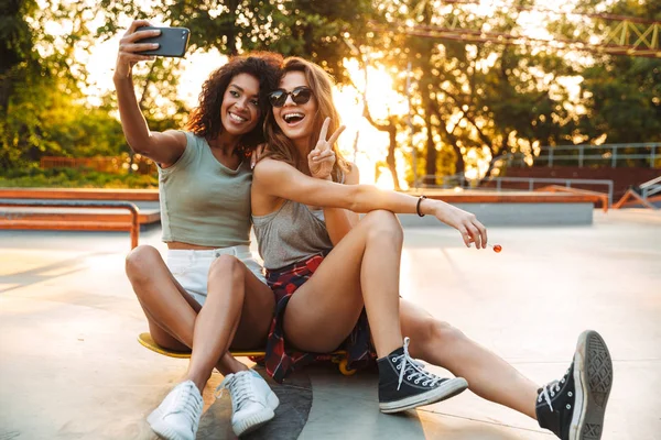 Twee Glimlachend Jonge Meisjes Plezier Terwijl Zittend Een Skateboard Het — Stockfoto