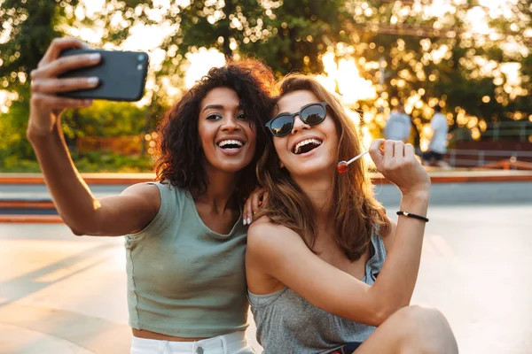 Two Smiling Young Girls Having Fun While Sitting Taking Selfie — Stock Photo, Image