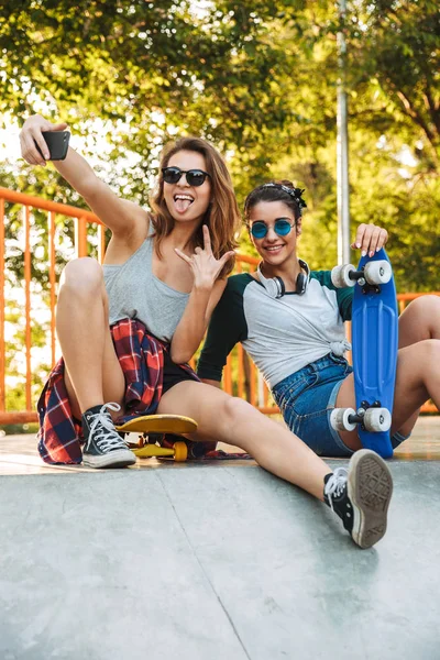 Két Vidám Fiatal Lányok Szórakozás Ülve Gördeszka Parkban Figyelembe Selfie — Stock Fotó