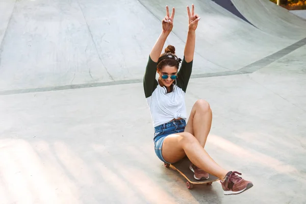 Happy young girl riding on a skateboard at a park