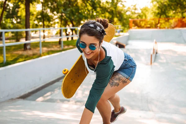 Vrolijke Jonge Meisje Eaephones Rijden Een Skateboard Een Park — Stockfoto