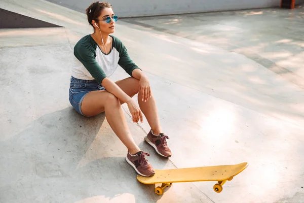 Positieve Meisje Koptelefoon Luisteren Naar Muziek Tijdens Vergadering Met Skateboard — Stockfoto