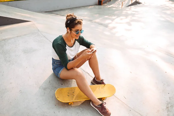 Pretty Young Girl Earphones Listening Music While Sitting Skateboard Park — Stock Photo, Image