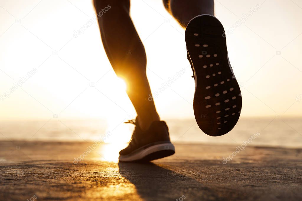 Back view of male sneakers running at the beach