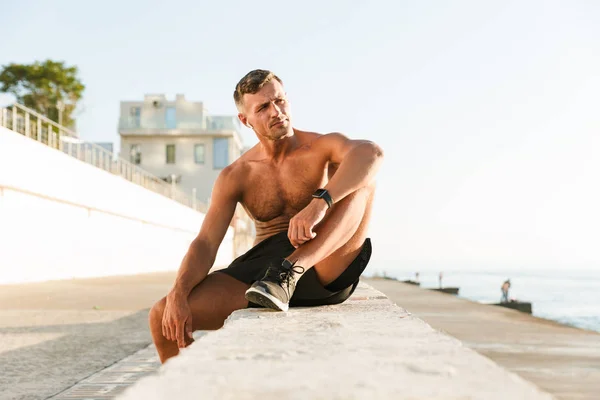 Charmant Sportif Concentré Torse Avec Écouteurs Vérifiant Montre Intelligente Assis — Photo