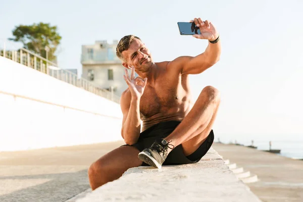 Selfie를 해변에 확인을 보여주는 이어폰 잘생긴 Shirtless 스포츠맨 — 스톡 사진