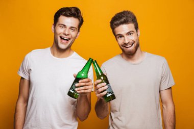 Sarı arka plan üzerinde izole bira şişeleri ile kızartma bir iki mutlu genç erkek arkadaşlarım portresi