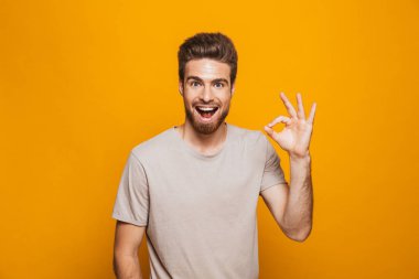 Ok hareket izole sarı arka plan üzerinde gösterilen mutlu bir genç adam portresi