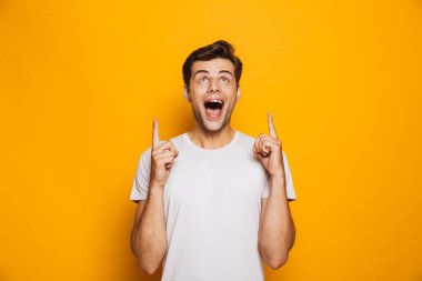Sarı arka plan üzerinde izole kopya alanı, parmakları işaret mutlu bir genç adam portresi