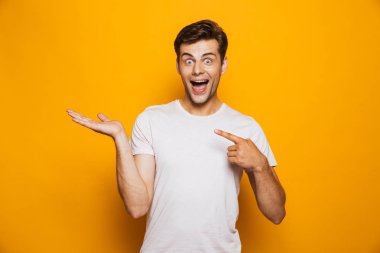 Neşeli bir genç adam onun Palm'da sarı arka plan üzerinde izole kopya alanı, parmakları işaret portresi