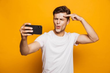 Sarı arka plan üzerinde izole bir selfie alarak heyecanlı bir genç adam portresi
