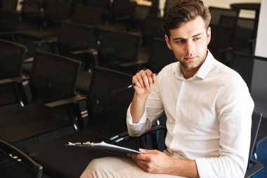 Bir tablet ile konferans odasında otururken yakışıklı resmi giyimli adam portresi