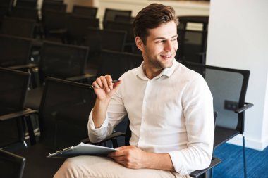 Bir tablet ile konferans odasında oturmuş bir emin yakışıklı resmi giyimli adam portresi