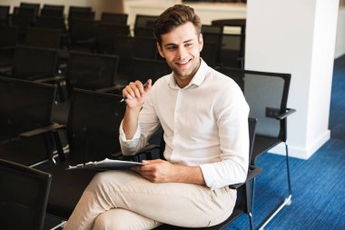 Bir tablet ile konferans odasında oturmuş bir gülümseyen yakışıklı resmi giyimli adam portresi