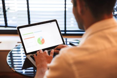 Otel lobisinde verimlilik grafik ile dizüstü bilgisayar üzerinde çalışan bir adamın üstten görünüm