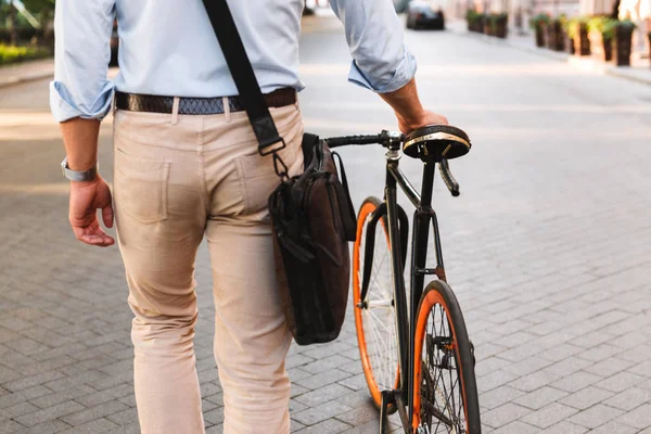 バッグ自転車で街の通りを歩くとシャツを着た若い男性の画像の背面図をトリミング — ストック写真