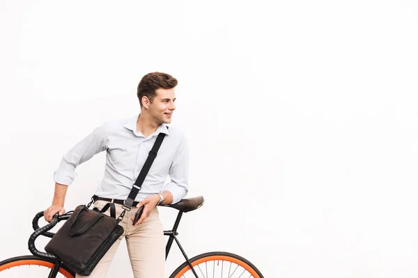 白い壁の上に立って よそ見しながら自転車に乗って傾いてシャツに身を包んだ幸せな若い男の肖像 — ストック写真