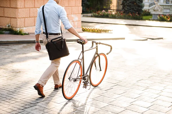 自転車で街の通りの上を歩いてのシャツに身を包んだスタイリッシュな若者のイメージ背面図をトリミング — ストック写真