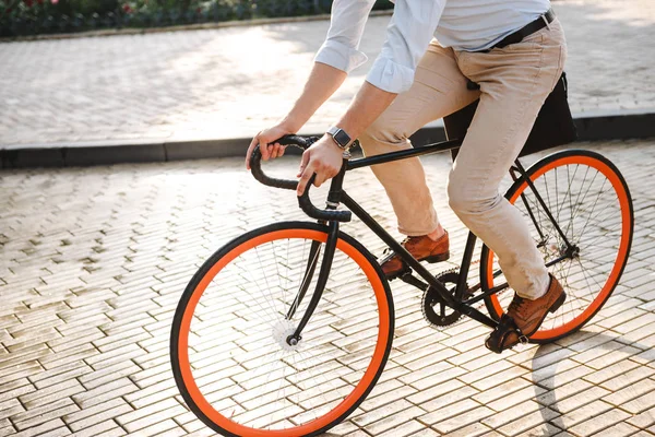 在城市街道上骑自行车的年轻人穿着衬衫的裁剪图像 — 图库照片