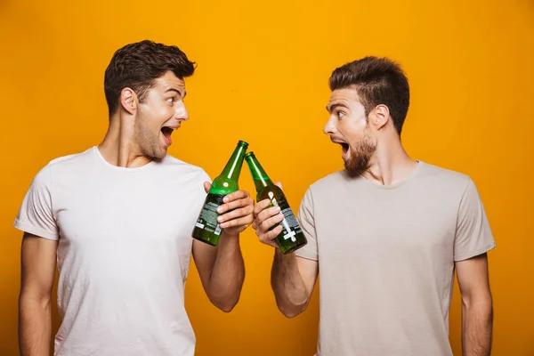 二人の陽気な若いです男ベスト友人Toastingとともにビールボトル隔離上の黄色の背景 — ストック写真