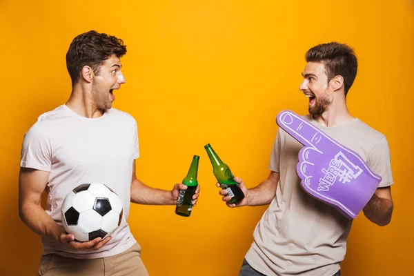 ビール瓶と乾杯と黄色の背景上で分離叫んでサッカー ボールと つの幸せな若い男性の肖像画ベスト フレンド — ストック写真