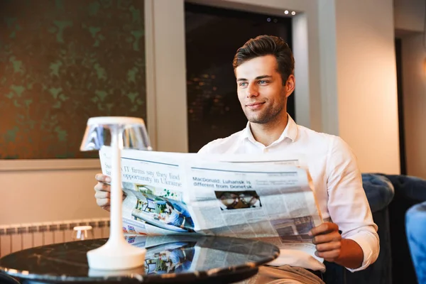 Sonriente Joven Formal Vestido Hombre Leyendo Periódico Mientras Sienta Vestíbulo —  Fotos de Stock