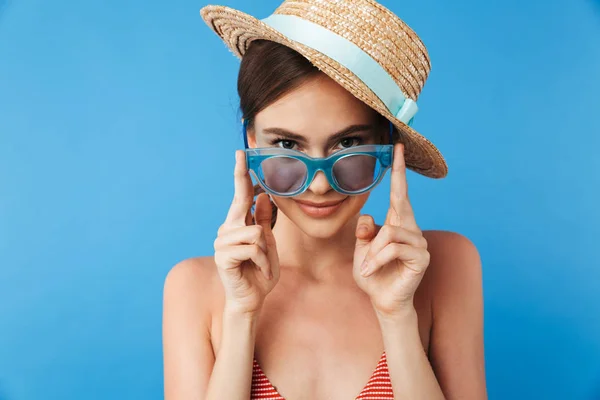 サングラスと青い背景に分離された夏帽子ポーズを身に着けている水着で笑顔の少女の肖像画 — ストック写真
