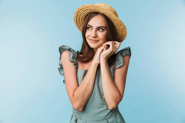 一个漂亮的年轻女子的肖像在礼服和夏天的帽子摆在蓝色背景孤立 — 图库照片