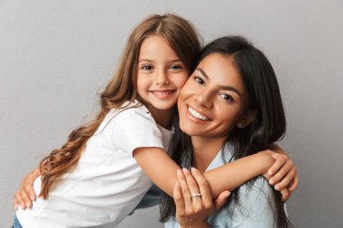 Gülümseyen ve birlikte sarılma küçük kızı ile çekici kadın fotoğrafı gri arka plan üzerinde izole