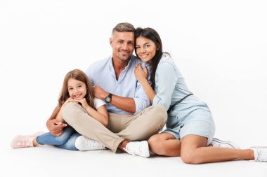 Mutlu bir aile baba, Anne, küçük kızı ise birlikte oturan ve gri arka plan üzerinde izole kamera bakarak sarılma portresi