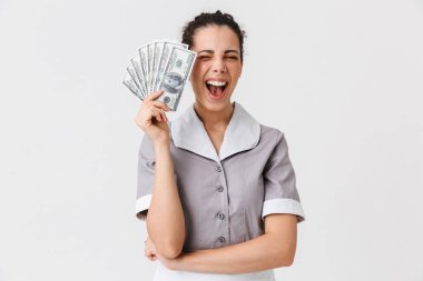 Neşeli bir genç hizmetçi portresi beyaz arka plan üzerinde izole para banknot tutan üniforma giymiş