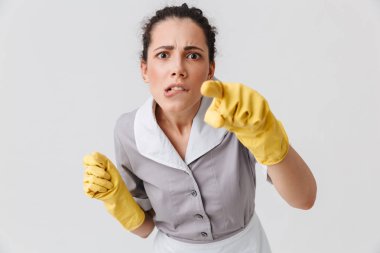 Beyaz arka plan üzerinde izole kamera işaret üniforma ve lastik eldiven portresi ciddi bir genç hizmetçi giymiş