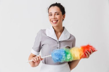 Beyaz arka plan üzerinde izole bir toz bezi tutan üniformalı bir gülümseyen genç hizmetçi portresi giyinmiş