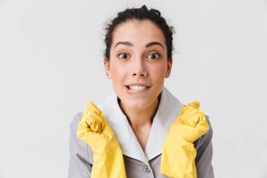 Beyaz arka plan üzerinde izole kamera bakarak üniforma ve lastik eldiven giymiş bir heyecanlı genç hizmetçi portresi