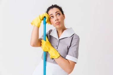 Düşünceli bir genç hizmetçi portresi beyaz arka plan üzerinde izole bir bez üzerine eğilerek üniforma giymiş