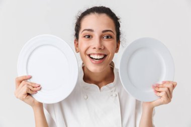 Tek tip gösteren iki tabak beyaz arka plan üzerinde izole bir mutlu genç kadın aşçı portresi giymiş