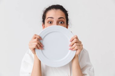 Tek tip bir tabak beyaz arka plan üzerinde izole gösteren bir neşeli genç kadın aşçı portresi giyinmiş