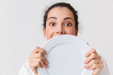 Tek tip bir tabak beyaz arka plan üzerinde izole gösteren giyinmiş bir neşeli genç kadın aşçı portresi kapatın