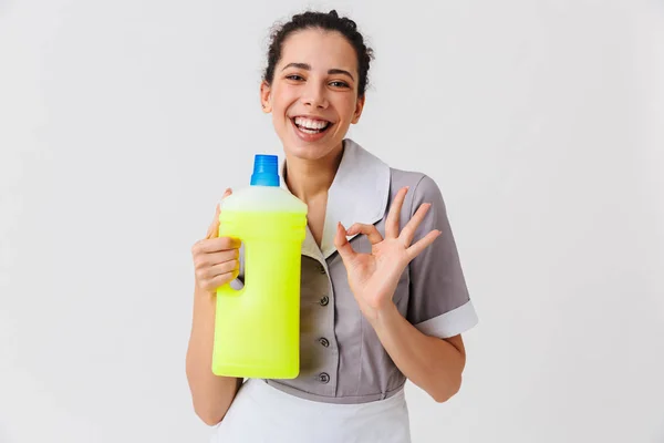 Retrato Uma Jovem Empregada Vestida Uniforme Segurando Detergente Mostrando Isolado — Fotografia de Stock