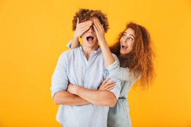 Sevimli kıvırcık kadın arkadaşı sarı arka plan üzerinde izole ayakta gözünde kapsayan görüntüsünü.