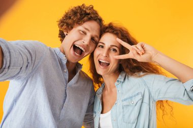 İki beyaz insanlar erkek ve kadın üzerinde sarı arka plan izole gülümseme ile barış işareti gösterilen süre selfie fotoğrafta görüntü