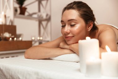 Şaşırtıcı genç güzel kadın görüntüsünü spa masaj odasında mum üzerinde yatıyor.