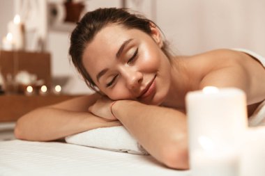 Şaşırtıcı genç güzel kadın görüntüsünü spa masaj odasında mum üzerinde yatıyor.