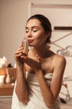 Vücut losyonu spa merkezinde tutarak havlu sarılı sağlıklı bir genç kadın portresi