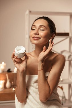 Çekici bir genç kadın vücut kremi spa merkezi uygulama bir havlu sarılı portresi