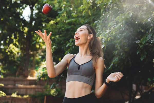 Portrait Excited Young Fitness Girl Throwing Apple Outdoors — Stock Photo, Image