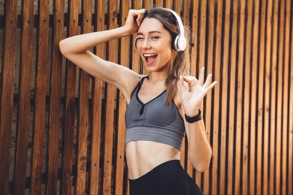 Portrait Smiling Young Fitness Girl Listening Music Wireless Headphones Showing — Stock Photo, Image