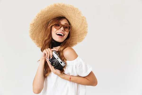 トレンディなパパラッチ女性 代の身に着けている麦わら帽子と白い背景上分離されたレトロなカメラを保持しているサングラスの写真 — ストック写真